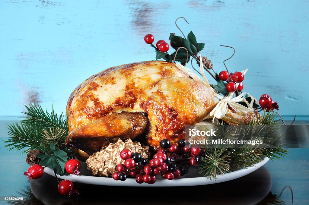 Scrumptious roast turkey chicken Scrumptious roast turkey chicken on platter with festive decorations for Thanksgiving or Christmas lunch, against shabby chic aqua blue rustic wood background. Roast Turkey Stock Photo