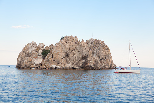 sailing near big rock in Black Sea , Crimea .