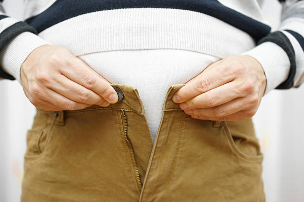 unable to close his pants because of gaining weight stock photo