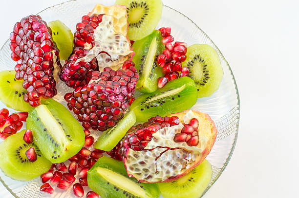 Pomegranate arils, blueberries and diced kiwifruit in a square bowl isolated on white background