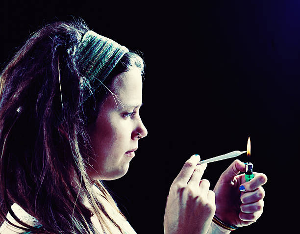 istock Serious young woman lighting marijuana joint 523832545