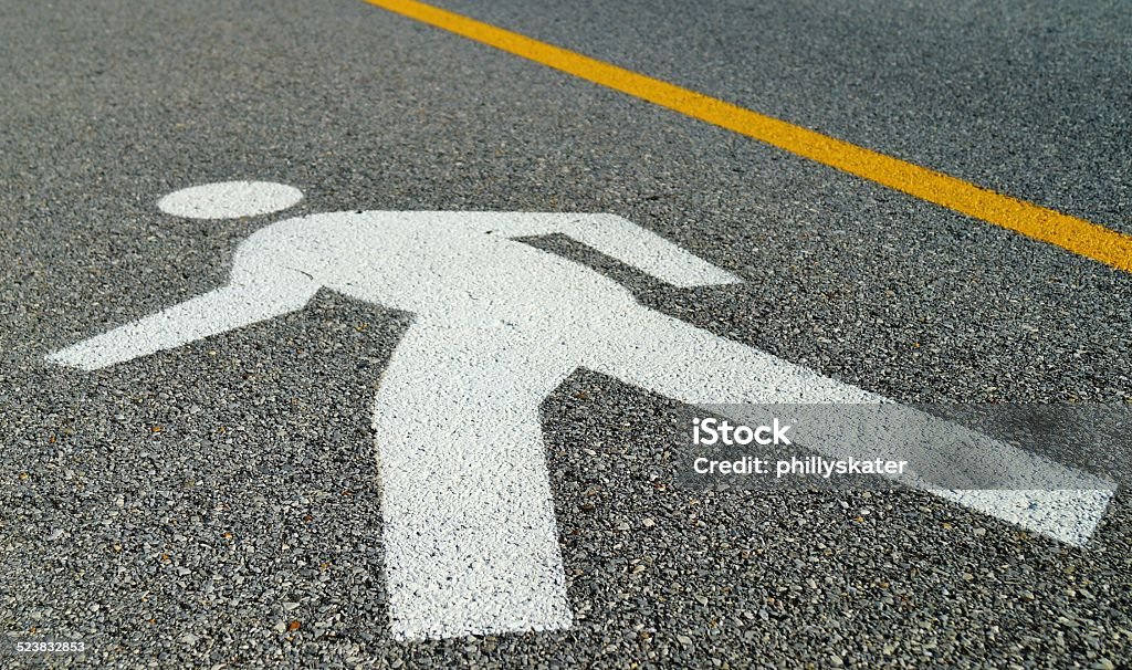 Man Crossing Road Sign Silhouette of a person walking painted on the street marking a pedestrian crossing. Adult Stock Photo