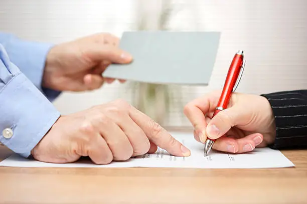 Photo of employer shows employee where to sign and giving her booklet