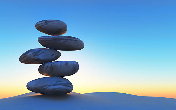 istock 3D balancing pebbles on sand against a sunset sky 523856128