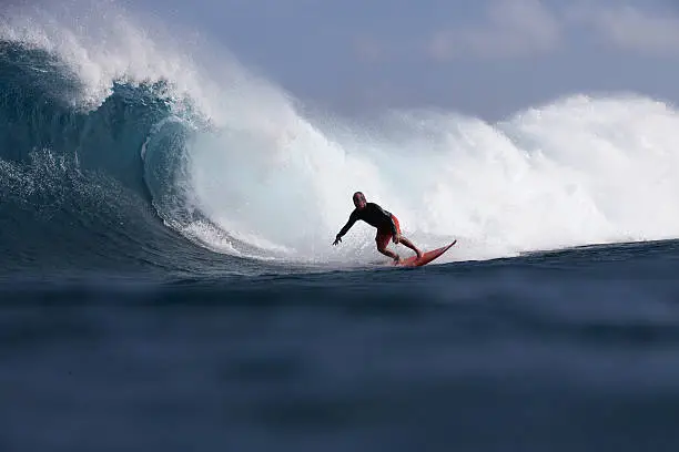An older man bottom turns on a big barreling wave in the Pacific Ocean