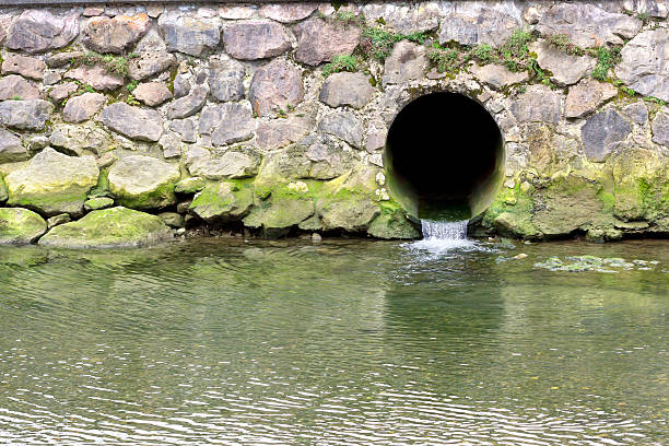 Background image of a stone wall with green mud and a drainage pipe with sewage water.