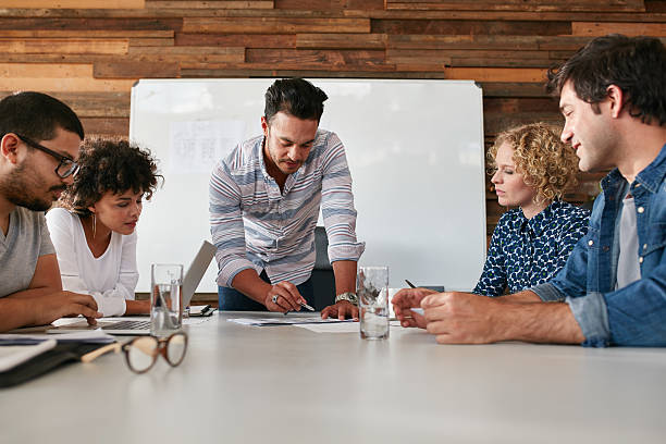 Creative team discussing new ideas on table Startup team working and planning in the meeting. Team of young professional discussing new creative ideas on table in boardroom. travel agency stock pictures, royalty-free photos & images