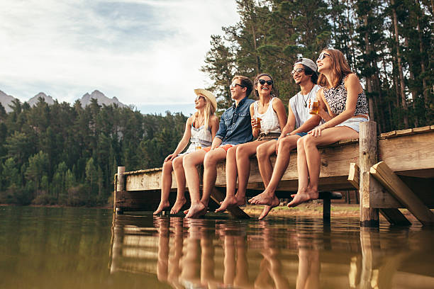 grupo de amigos sentado no lago no pontão - forest sitting men comfortable imagens e fotografias de stock