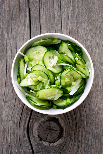 Cucumber salad on wooden background, top view