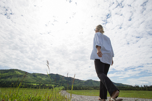 Woman walks along rural path towards hills, through ranchlands