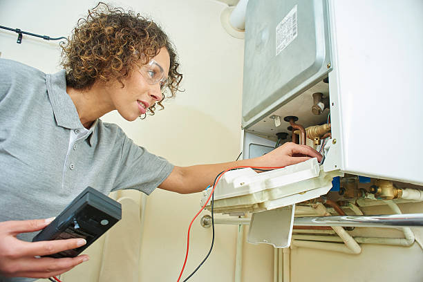 female plumber with central heating a female electrician is electrically testing a central heating boiler . boiler photos stock pictures, royalty-free photos & images