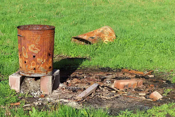 Photo of Image of rusty garden waste incinerator bin, on lawn grass