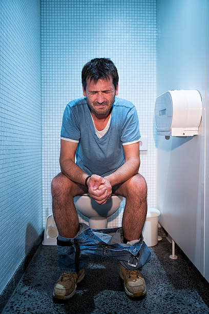 mann sitzt in öffentliche toilette - facial expression unpleasant smell shirt caucasian stock-fotos und bilder