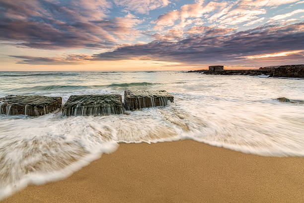 istock waves, rocks and sand at sunset on the beach 523873024