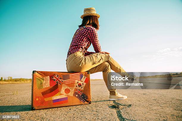 Traveler Sits On Suitcase With Stamps Flags Stock Photo - Download Image Now - Suitcase, Old-fashioned, Retro Style