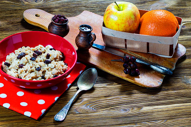 Oatmeal with raisins in a red ceramic plate on a wooden table. The concept of a healthy breakfast. Healthy lifestyle.