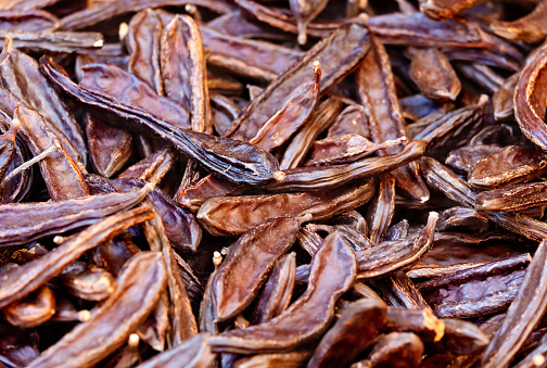 Carob Beans, sometimes called Locust Beans, for Sale at an Italian Market in Southern Italy. The beans are sometimes referred to as Poor Man’s Chocolate. Although not as tasty as cocoa beans the ground dried edible pulp resembles cocoa powder, but lacks the flavour and texture of chocolate.