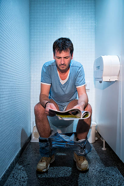 mann sitzt in öffentliche toilette - facial expression unpleasant smell shirt caucasian stock-fotos und bilder