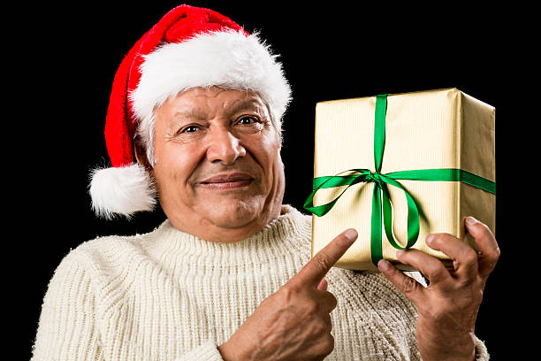 istock Male Senior With Santa Cap Pointing At Golden Gift 523876265