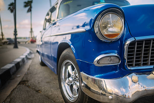 Front end of Vintage American car parked on the street of Old Havana.  Typical busy street for Cuban capital. Selective focus on front end of the car.
