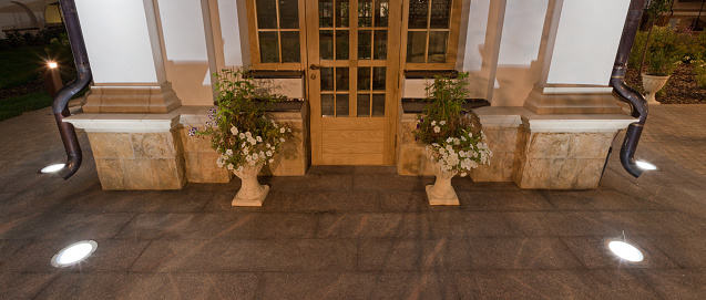 Embedded in the granite pavement lights. Lighting of the sidewalk. A vase of flowers and the door to the chapel