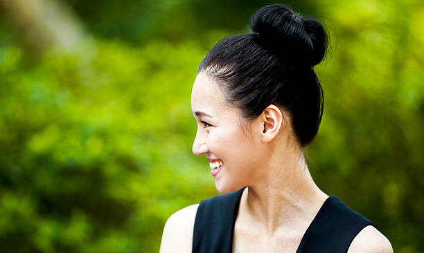 felice donna asiatica sorridente in natura - hair bun asian ethnicity profile women foto e immagini stock