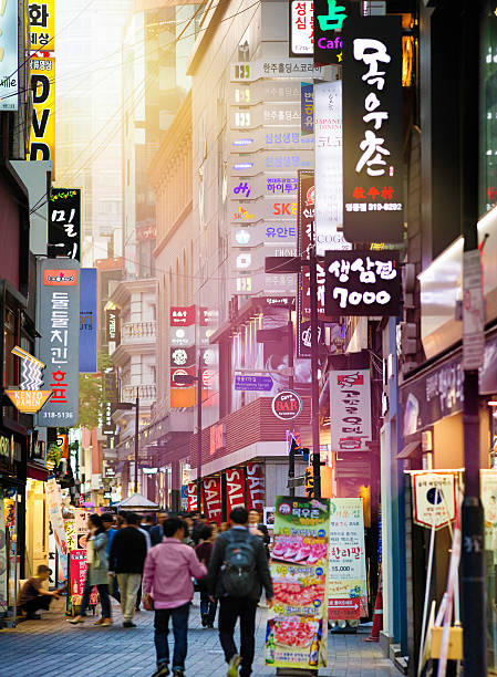 Seoul Myeongdong shopping street at sunset with sunlight piercing through the advertising signs.
