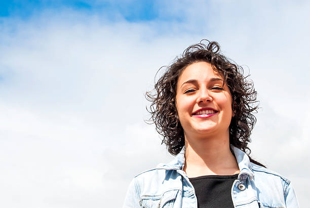 istock Beautiful woman with a sky with clouds background 523885378
