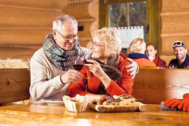 sênior casal tendo almoço depois de esquiar, brindando vinho wiht - apres ski couple love winter - fotografias e filmes do acervo