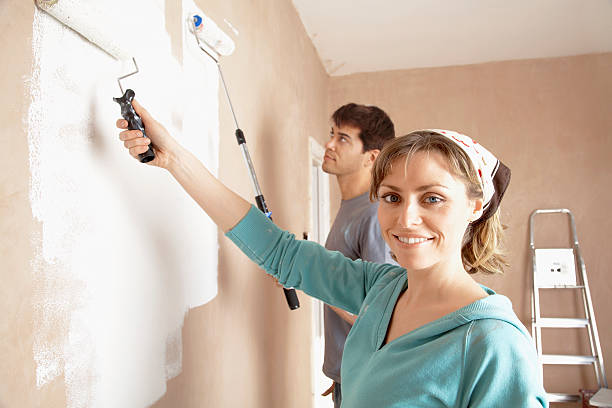 istock Woman And Man Painting Wall With Paint Rollers 523894913