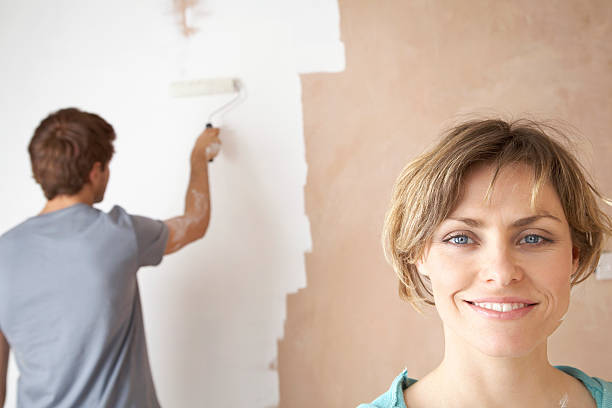 istock Happy Woman With Man Using Paint Roller On Wall 523894925