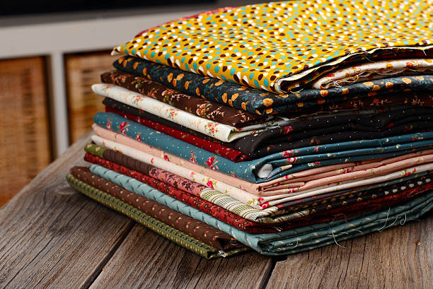 istock heap of cloth fabrics on wooden table 523895349