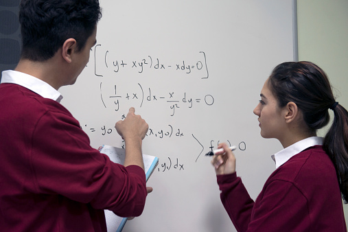 Two students doing math at the whiteboard, Istanbul, Turkey. Young man talking, female student listening. Nikon D800, full frame.
