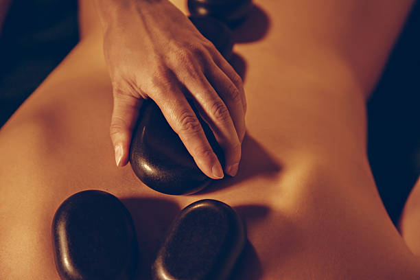 istock Masseuse Placing Hot stones On A Woman's Back 523899769