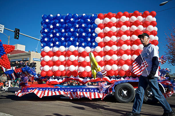 Albany, Oregon, USA - November 11, 2014: This part of the parade on Lyon Street and 2nd Ave has a float with a USA Flag made of balloons. This is a float entered by Hewlett Packard Corporation. A man with a small flag is walking along the side. Also blurred images of spectators can be seen in the background. This large Veteran's Day Parade is held annually in Albany, Oregon.