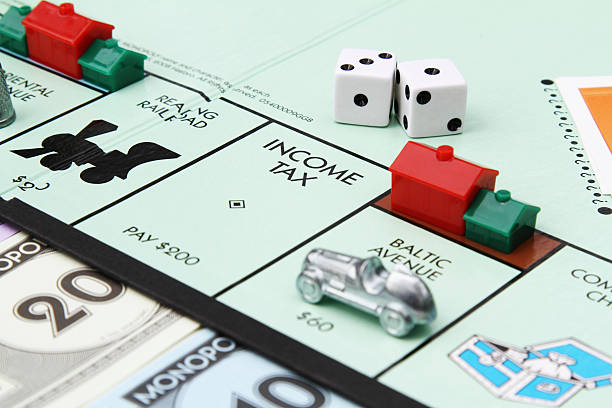 West Palm Beach, USA - April 16, 2013: A partial view of a Monopoly game board showing the Income Tax space with race car, dice, hotel and house game pieces placed on the board. Monopoly is a popular board game that is owned and distributed by Hasbro.
