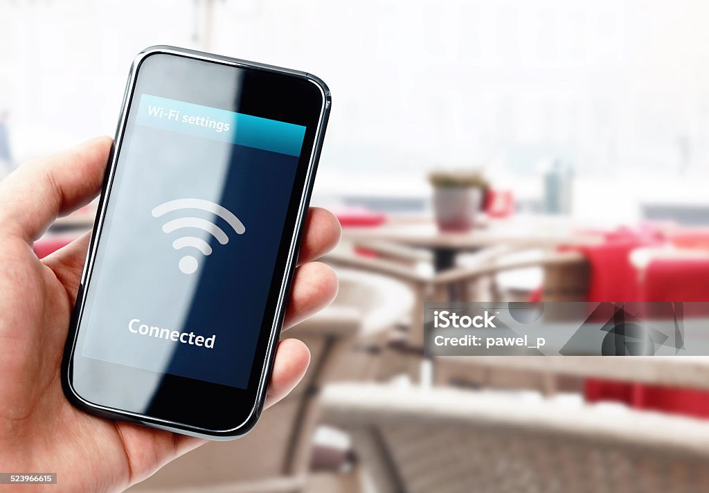 Hand holding smartphone with wi-fi connection in cafe Hand holding smartphone with wi-fi connection on the screen in cafe Wireless Technology Stock Photo