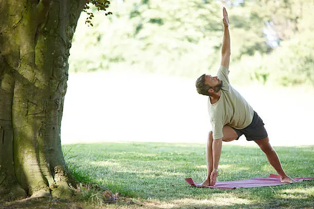 Full length shot of a handsome mature man doing yoga outdoors