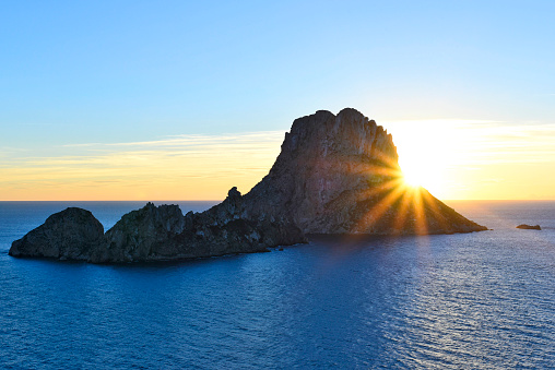 Sunset at the magic rock Es Vedra on Ibiza island. Sunbeam behind the island.