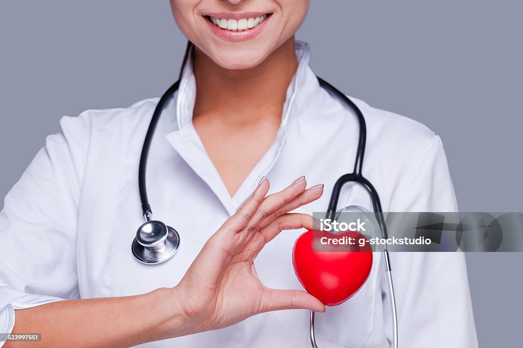 In love with her profession. Close-up of female doctor in white uniform holding heart prop and smiling Cardiologist Stock Photo