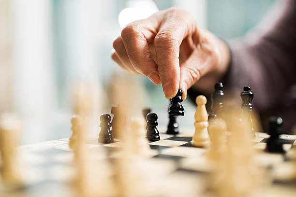 Playing chess. Unrecognizable senior person playing chess. chess stock pictures, royalty-free photos & images