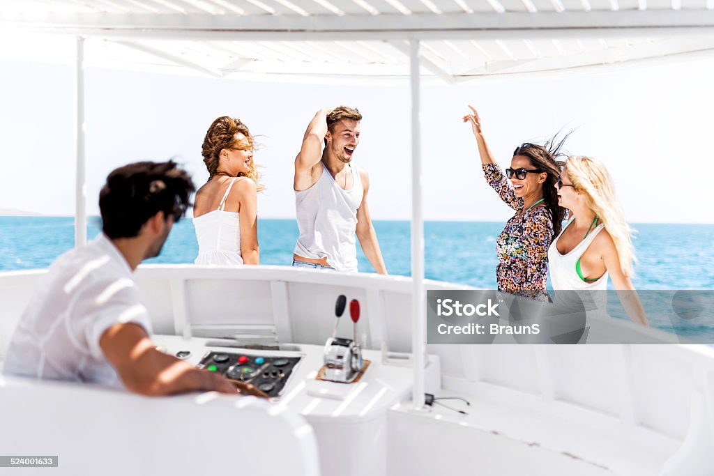 Having fun on yacht. Group of happy young people enjoying in summer day on a boat and dancing. Focus is on background. Yacht Stock Photo