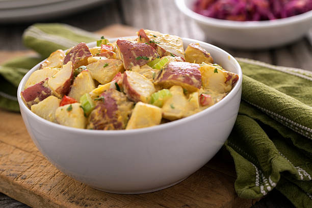 A bowl of potato salad and red cabbage coleslaw on rustic wood picnic table.  Please see my portfolio for other food and drink images. 
