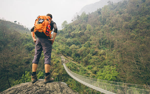 Hiker man standing on rock Hiker man standing on rock with mountain suspension bridge in front himalayas photos stock pictures, royalty-free photos & images