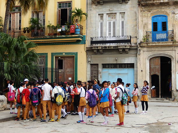 Havana, Cuba - January 20, 2016: A group of cuban schoolchildren dressed in yellow school uniforms waiting in front of the school in Old Havana, Cuba