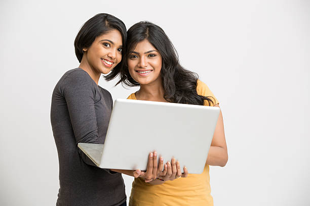 istock Cheerrful two young girls posing with laptop 524014428