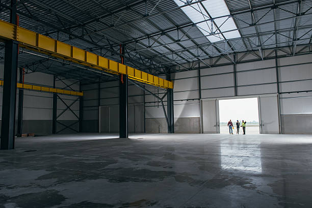 Architect team At Work Site With Blueprints Architect team At Work Site With Blueprints standing at big hangar doors industrial building stock pictures, royalty-free photos & images