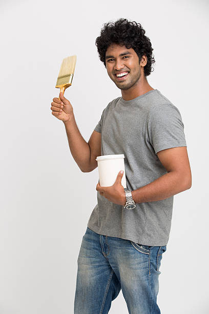 radosny młody mężczyzna trzymając narzędzia do malowania pracy - house painter home improvement paint can painter zdjęcia i obrazy z banku zdjęć