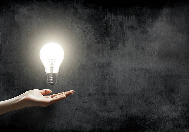istock businesswoman holding Light bulb lamp on blackboard background 524022457