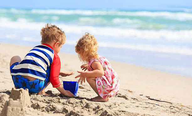 kids play with sand on summer beach stock photo
